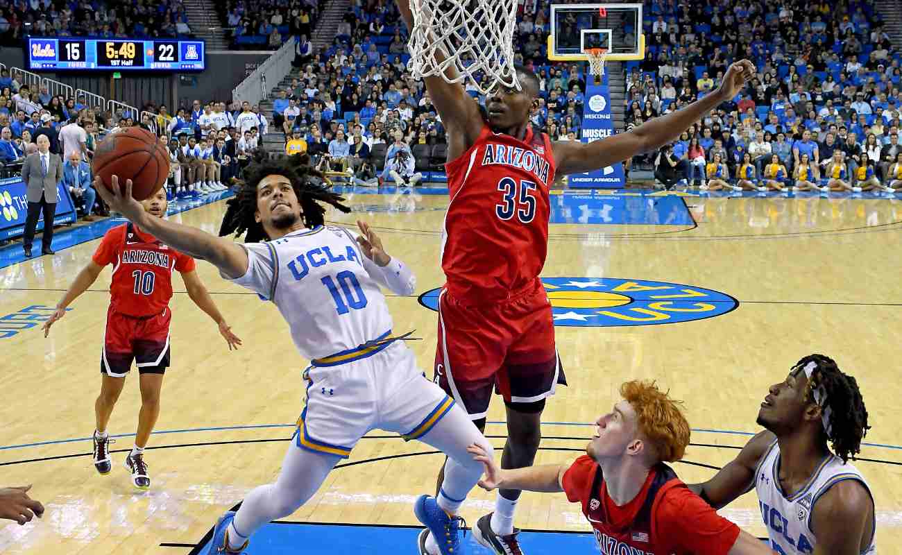 Tyger Campbell #10 of the UCLA Bruins gets by Christian Koloko #35 of the Arizona Wildcats for a basket in the game