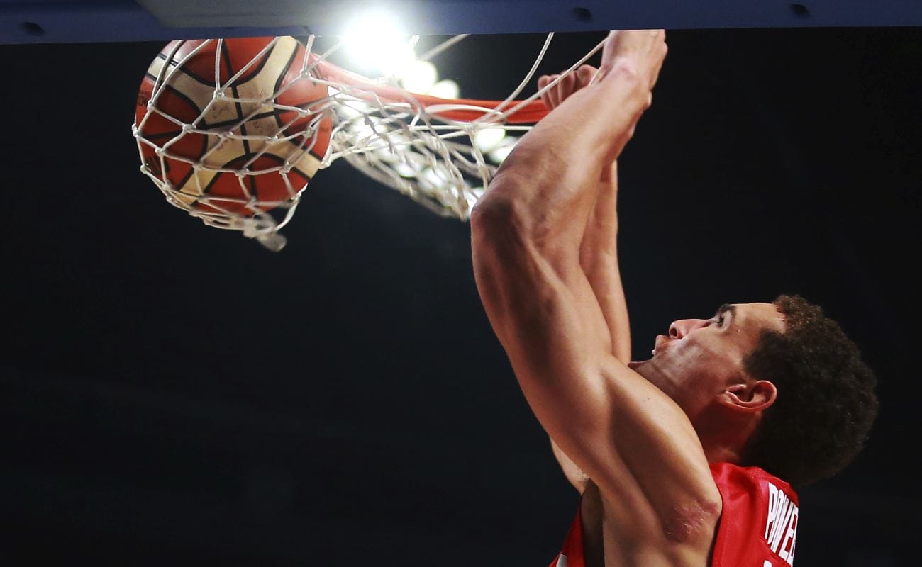 Dwight Powell flies to dunk basketball in the net during a game. 