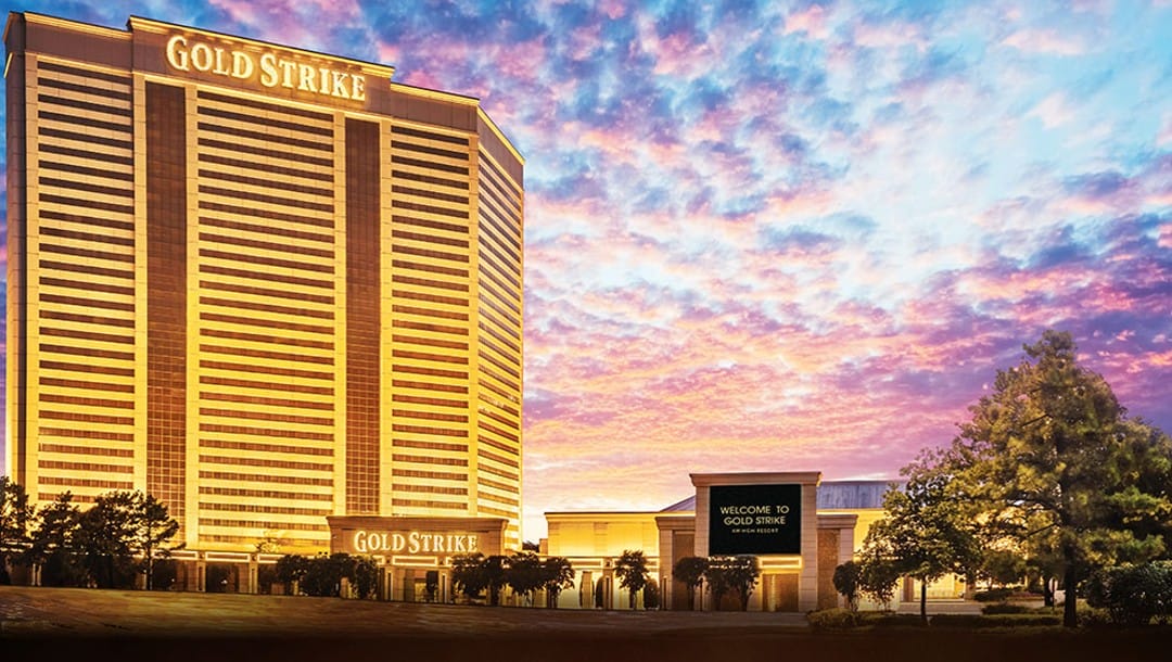 The Gold Strike Casino building illuminated in gold lights during sunset.