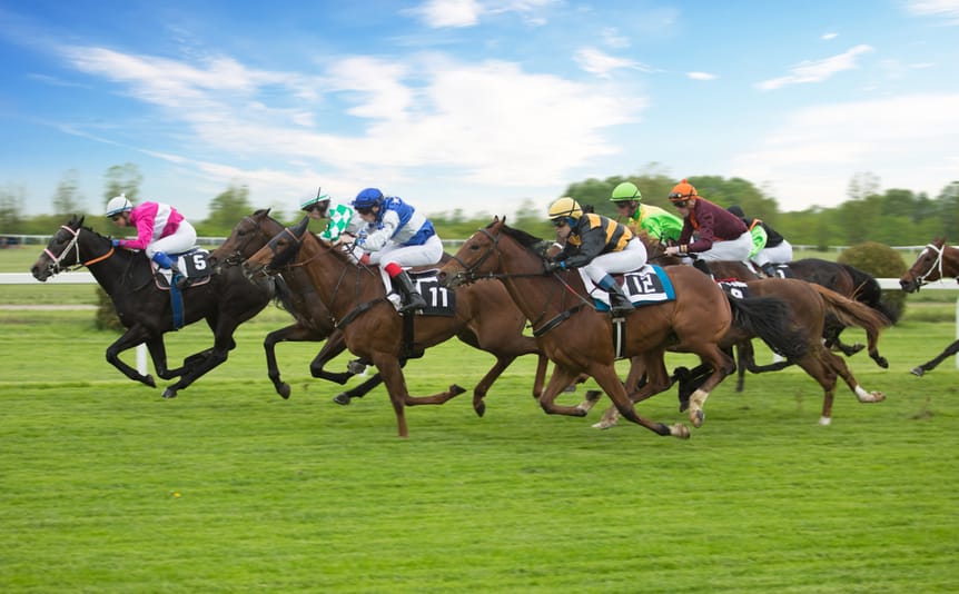 Horses and jockeys race along a track.