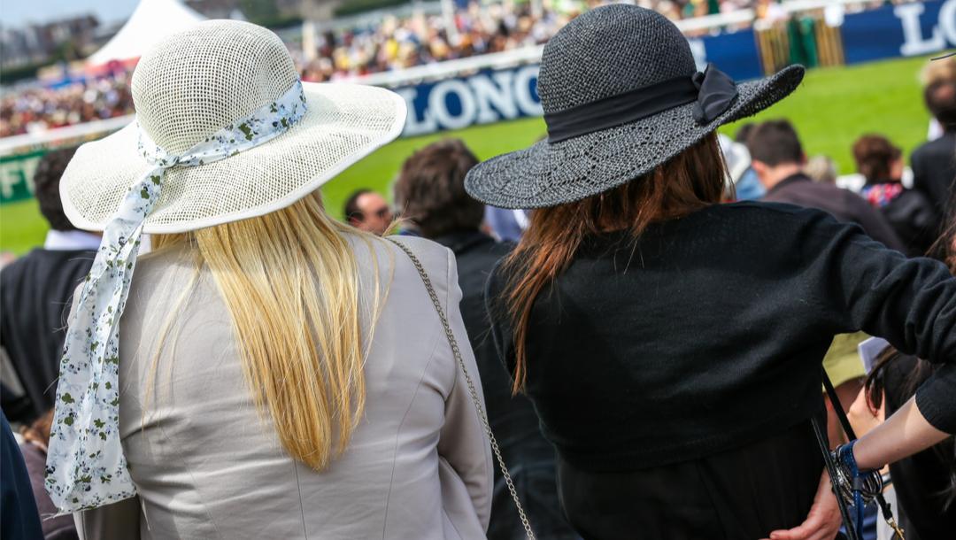 Elegant women with hats watching a horse race.