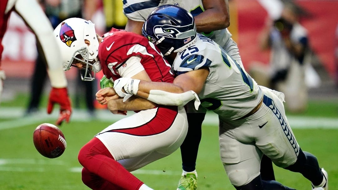 Arizona Cardinals punter Andy Lee, left, loses the ball on a punt attempt as he is wrapped up by Seattle Seahawks running back Travis Homer (25) during the second half of an NFL football game Sunday, Jan. 9, 2022, in Glendale, Ariz. (AP Photo/Darryl Webb)