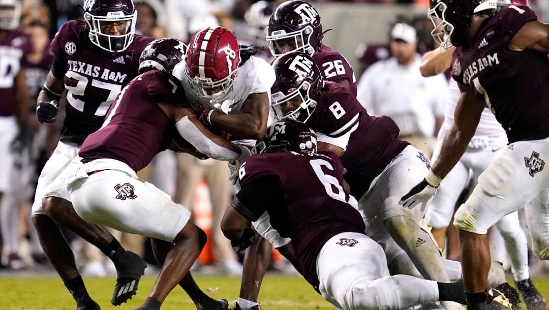 Alabama wide receiver John Metchie III (8) is tackled Texas A&M defensive back Tyreek Chappell (7), defensive lineman Adarious Jones (6) and DeMarvin Leal (8) after catch and run during the second half of an NCAA college football game on Saturday, Oct. 9, 2021, in College Station, Texas. (AP Photo/Sam Craft)