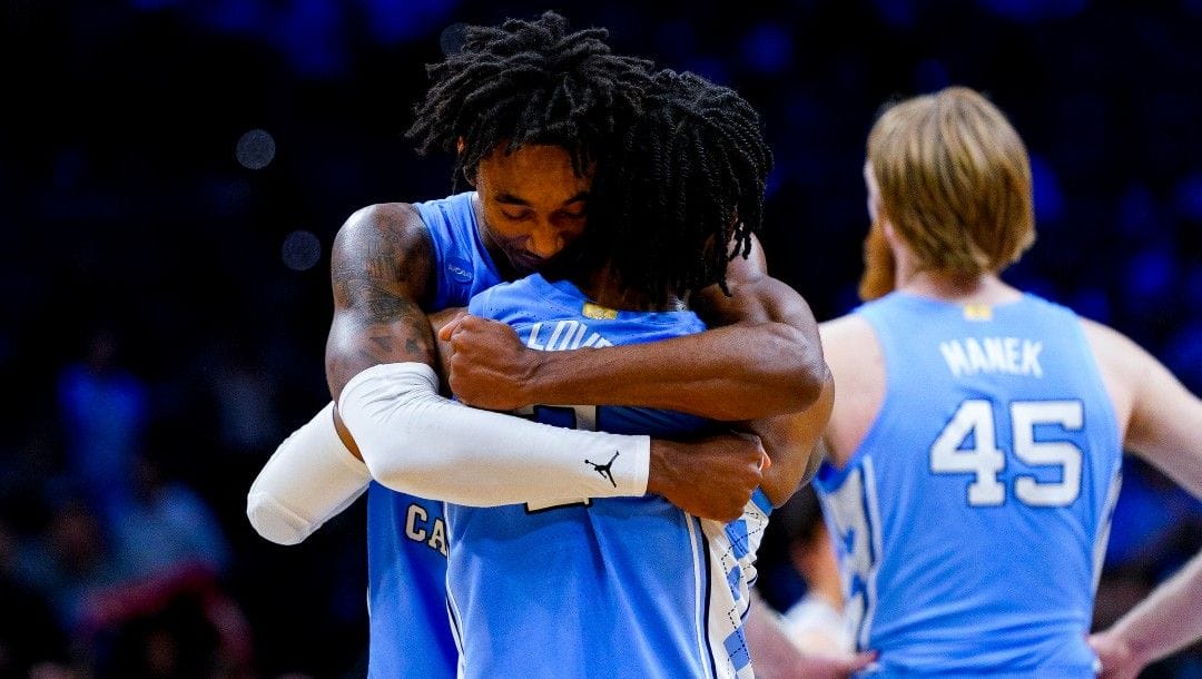 North Carolina's Leaky Black, left, gives North Carolina's Caleb Love, center, a hug following the second half of a college basketball game against UCLA in the Sweet 16 round of the NCAA tournament, Friday, March 25, 2022, in Philadelphia.