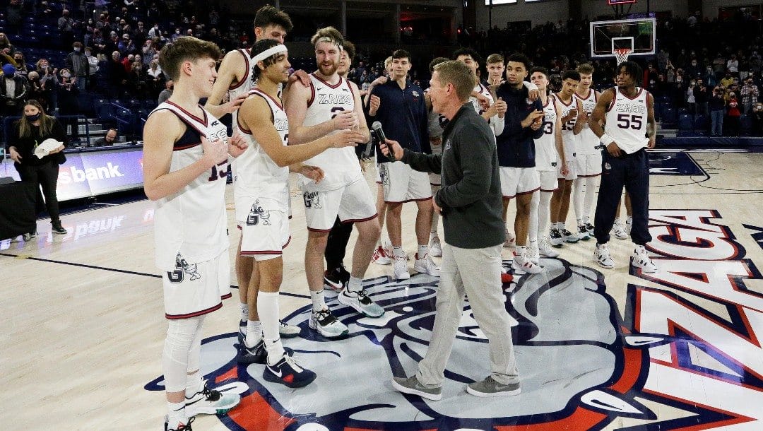 Gonzaga head coach Mark Few, center, prepares to hand a microphone to guard Andrew Nembhard, second from the left, during senior night.