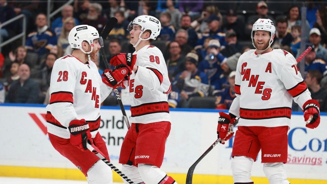 Carolina Hurricanes' Martin Necas (88) celebrates with Carolina Hurricanes' Ian Cole (28) and Carolina Hurricanes' Jaccob Slavin (74) after scoring a goal during the first period of an NHL hockey game against the St. Louis Blues on Saturday, March 26, 2022 in St. Louis.