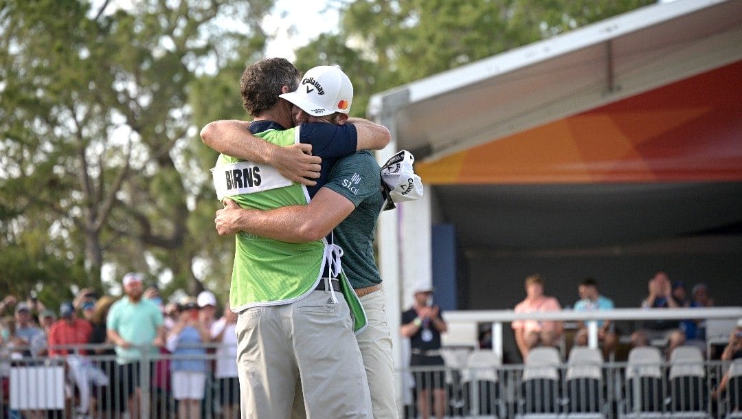 Sam Burns, right, celebrates with his caddie after sinking a putt on the 18th green to win the Valspar Championship golf tournament.
