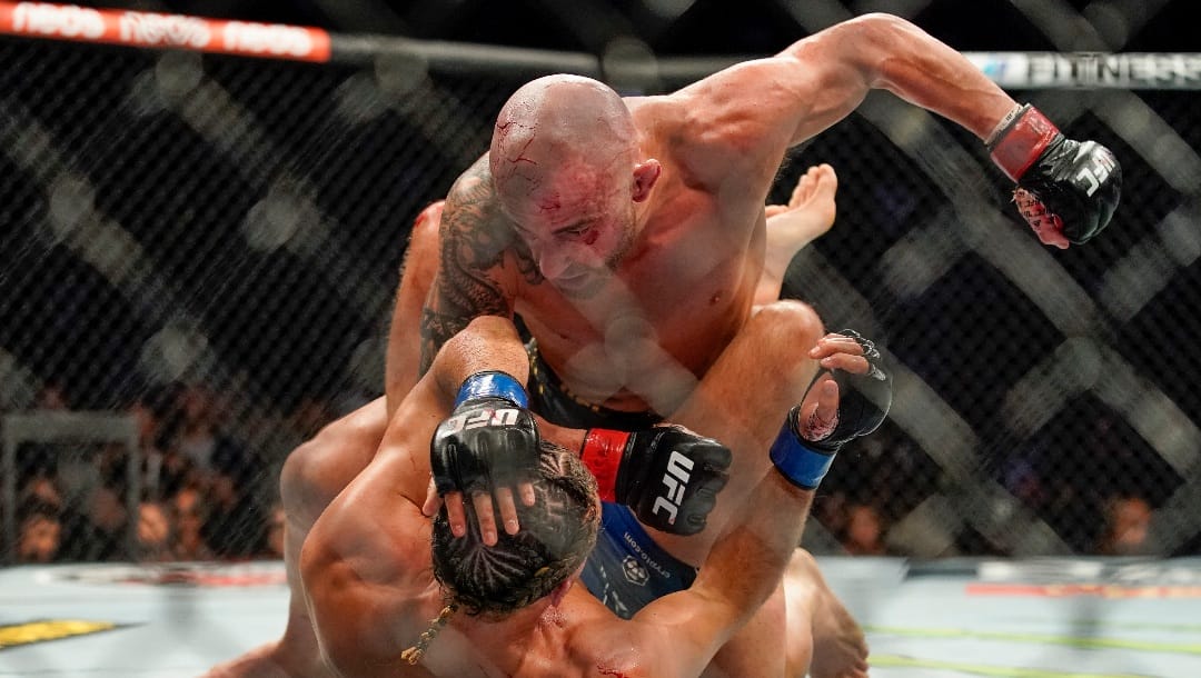 Alexander Volkanovski, top, punches Brian Ortega during a featherweight mixed martial arts title bout at UFC 266, Saturday, Sept. 25, 2021, in Las Vegas. (AP Photo/John Locher)