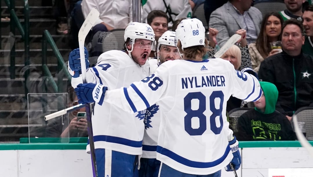 Toronto Maple Leafs center Auston Matthews, left, William Nylander (88) and Mark Giordano celebrate a goal scored by Matthews during the second period of the team's NHL hockey game against the Dallas Stars, Thursday, April 7, 2022, in Dallas. The goal was Matthews' 55th of the season. (AP Photo/Tony Gutierrez)