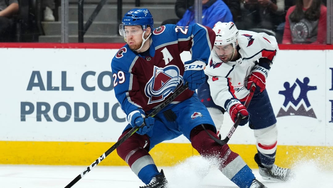 Colorado Avalanche center Nathan McKinnon (29) moves the puck around Washington Capitals defenseman Justin Schultz (2) during the first period of an NHL hockey game Monday, April 18, 2022, in Denver. (AP Photo/Jack Dempsey)