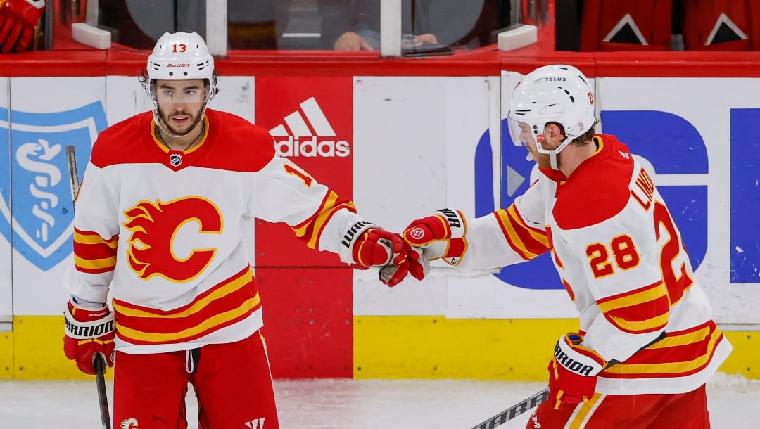 Calgary Flames left wing Johnny Gaudreau (13) is congratulated by center Elias Lindholm (28) after scoring an empty-net against the Chicago Blackhawks during the third period of an NHL hockey game, Monday, April 18, 2022, in Chicago.