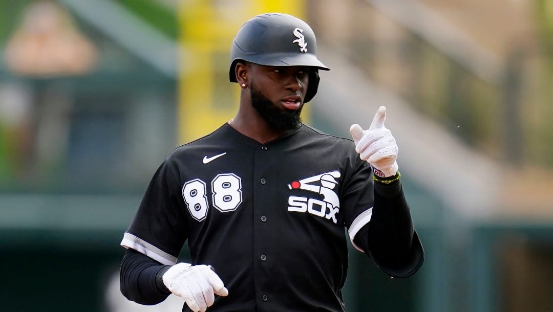 Chicago White Sox's Luis Robert points to teammates in the dugout after arriving at second base with a double against the Colorado Rockies during the first inning of a spring training baseball game Sunday, March 20, 2022, in Scottsdale, Ariz. (AP Photo/Ross D. Franklin)