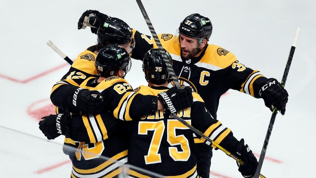 Boston Bruins' Brad Marchand (63) celebrates his goal with teammates Craig Smith (12), Connor Clifton (75) and Patrice Bergeron (37) during the second period in Game 6 of an NHL hockey Stanley Cup first-round playoff series against the Carolina Hurricanes, Thursday, May 12, 2022, in Boston.