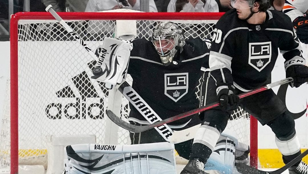 Los Angeles Kings goaltender Jonathan Quick, left, makes a pad save as defenseman Sean Durzi watches during the second period in Game 4 of an NHL hockey Stanley Cup first-round playoff series against the Edmonton Oilers Sunday, May 8, 2022, in Los Angeles.