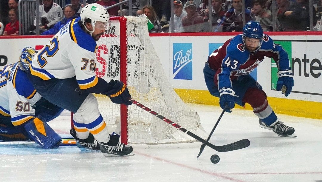 St. Louis Blues defenseman Justin Faulk (72) and Colorado Avalanche center Darren Helm (43) reach for the puck during the third period in Game 2 of an NHL hockey Stanley Cup second-round playoff series Thursday, May 19, 2022, in Denver.