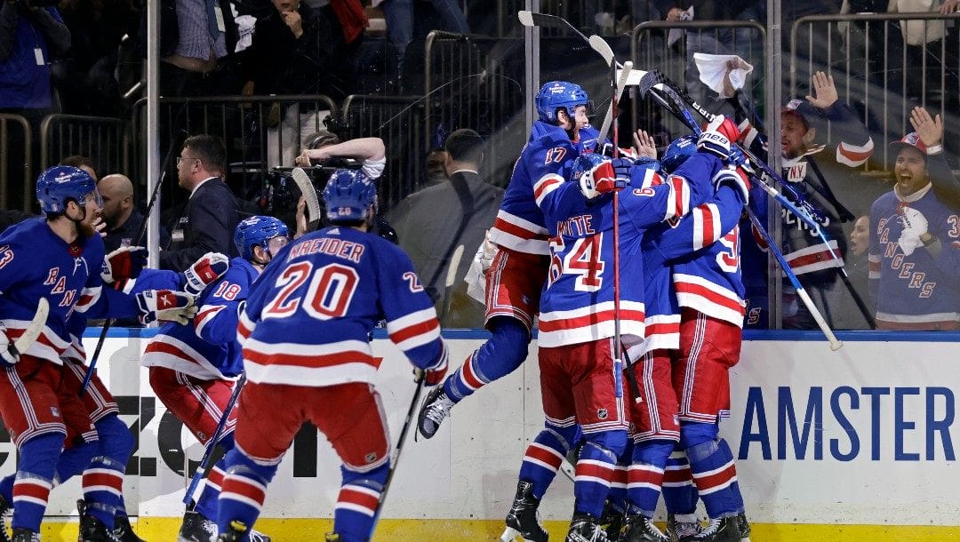 New York Rangers left wing Artemi Panarin is mobbed by teammates after scoring the game winning goal against the Pittsburgh Penguins during overtime in Game 7 of an NHL hockey Stanley Cup first-round playoff series, Sunday, May 15, 2022, in New York. The Rangers won 4-3 in overtime.