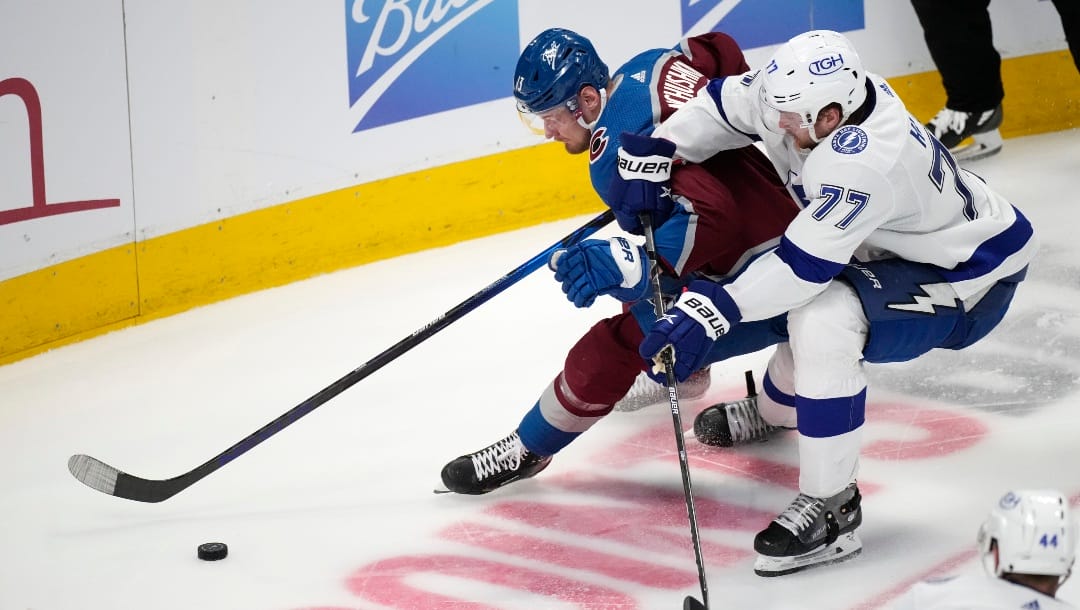 Colorado Avalanche right wing Valeri Nichushkin, left, looks to collect the puck as Tampa Bay Lightning defenseman Victor Hedman defends during the third period of an NHL hockey game Thursday, Feb. 10, 2022, in Denver. The Avalanche won 3-2. (AP Photo/David Zalubowski)