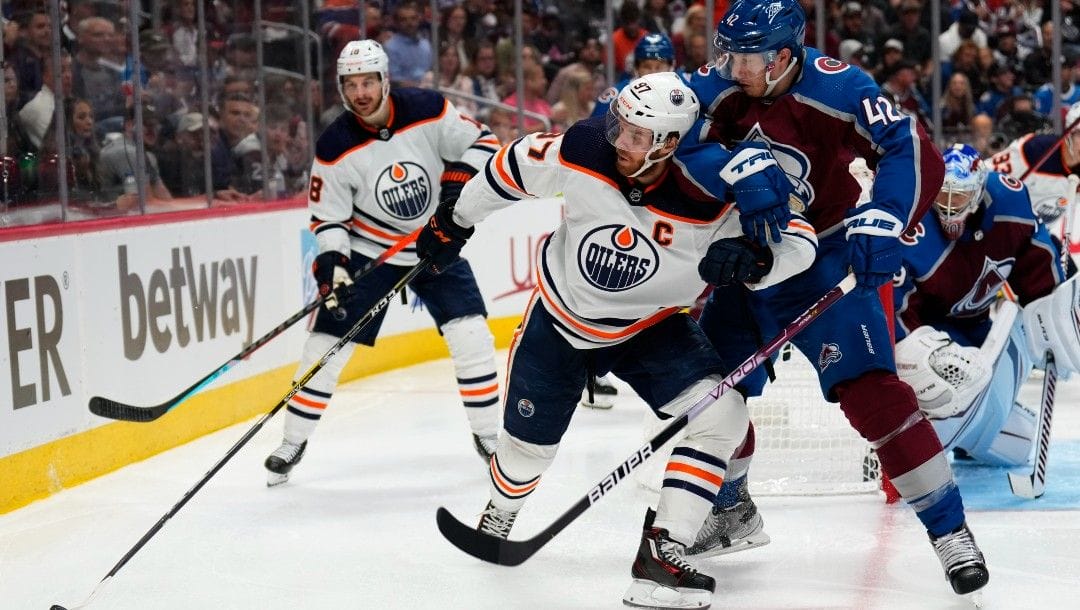 Edmonton Oilers center Connor McDavid (97) is pressured by Colorado Avalanche defenseman Josh Manson (42) during the third period in Game 2 of the NHL hockey Stanley Cup playoffs Western Conference finals Thursday, June 2, 2022, in Denver.