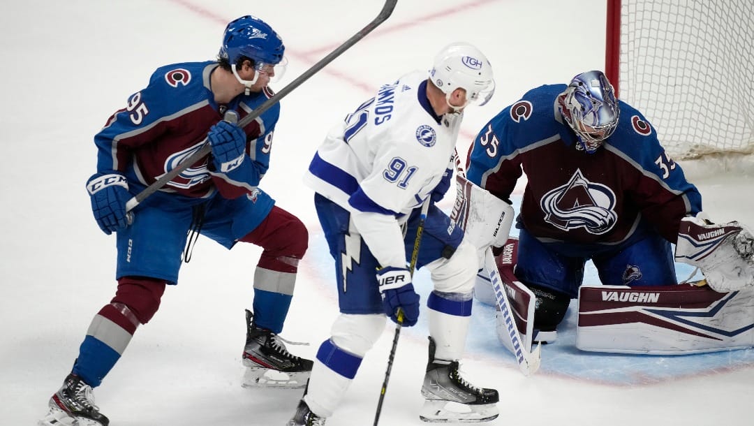 Tampa Bay Lightning center Steven Stamkos, center, puts a shot on Colorado Avalanche goaltender Darcy Kuemper, right, after slipping past Avalanche left wing Andre Burakovsky during the third period of an NHL hockey game Thursday, Feb. 10, 2022, in Denver. The Avalanche won 3-2. (AP Photo/David Zalubowski)