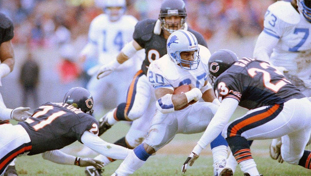 Detroit Lions' Barry Sanders (20) attempts to gain yardage as Chicago Bears' Donnell Woolford, left, and Shaun Gayle (23) tackle Sanders in 1990.
