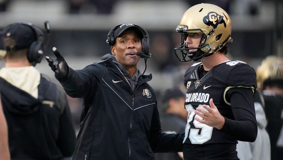 Colorado head coach Karl Dorrell, left, confers with punter Josh Watts in the second half of an NCAA college football game against Washington, Nov. 20, 2021, in Boulder, Colo.