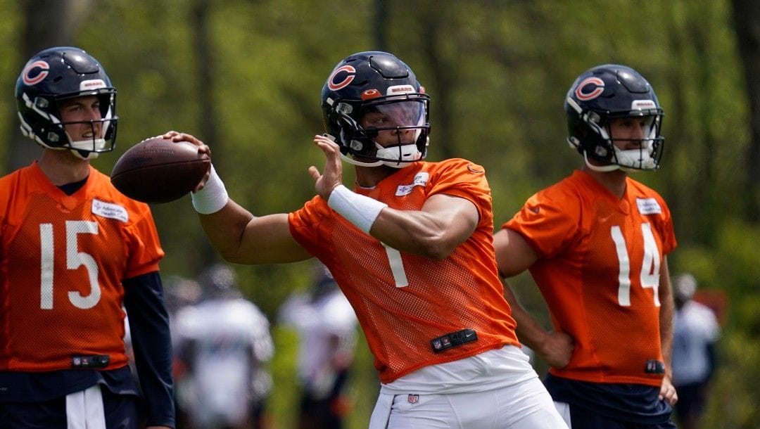 Chicago Bears quarterback Justin Fields throws a pass as quarterback Trevor Siemian, left, and quarterback Nathan Peterman look on at the NFL football team's practice facility in Lake Forest, Ill., Wednesday, May 17, 2022.