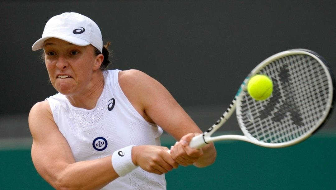 Poland's Iga Swiatek returns the ball to France's Alize Cornet during a third round women's singles match on day six of the Wimbledon tennis championships in London, Saturday, July 2, 2022.