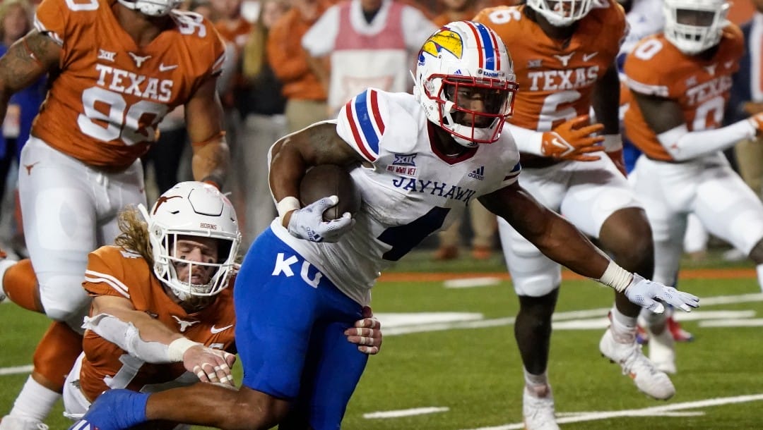 Kansas running back Devin Neal (4) runs past Texas defensive back Brenden Schooler (14) for a touchdown during the second half of an NCAA college football game in Austin, Texas, Saturday, Nov. 13, 2021.