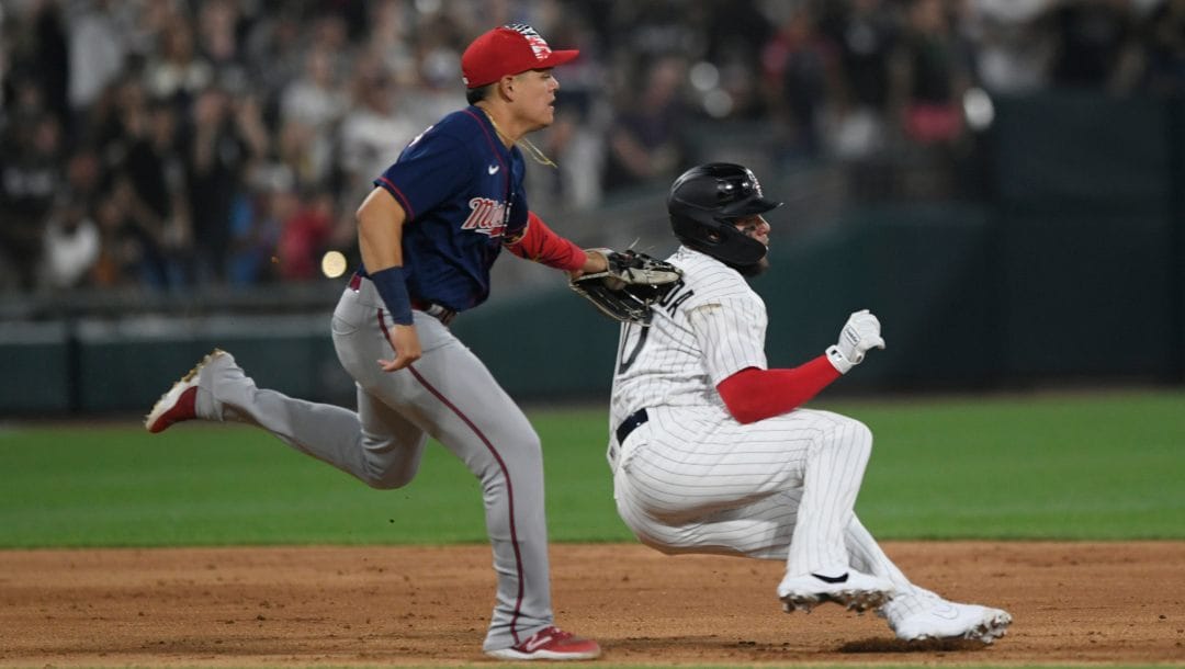 Chicago White Sox's Yoan Moncada right, is caught during a rundown by Minnesota Twins third baseman Gio Urshela left, during the seventh inning of a baseball game Monday, July 4, 2022, in Chicago.