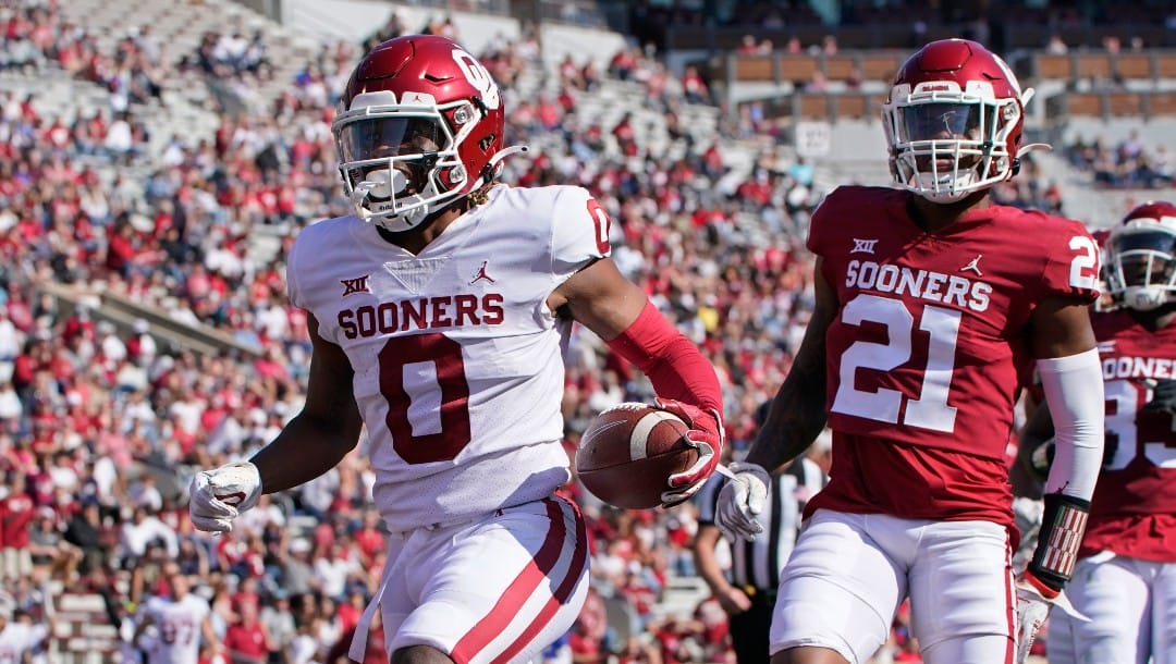 FILE - Oklahoma running back Eric Gray (0) runs into the end zone with a touchdown in front of defensive back Kendall Dennis (21) during the NCAA college football team's spring game in Norman, Okla., in this Saturday, April 24, 2021, file photo. The transfer portal was particularly active during the most recent offseason. The Tennessee presence is most notable at No. 2 Oklahoma. The Sooners have three former Vols in running back Eric Gray, defensive back Key Lawrence and offensive tackle Wanya Morris.(AP Photo/Sue Ogrocki, File)