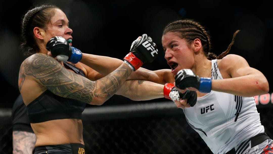 Julianna Pena, right, hits Amanda Nunes during a women's bantamweight mixed martial arts title bout at UFC 269.