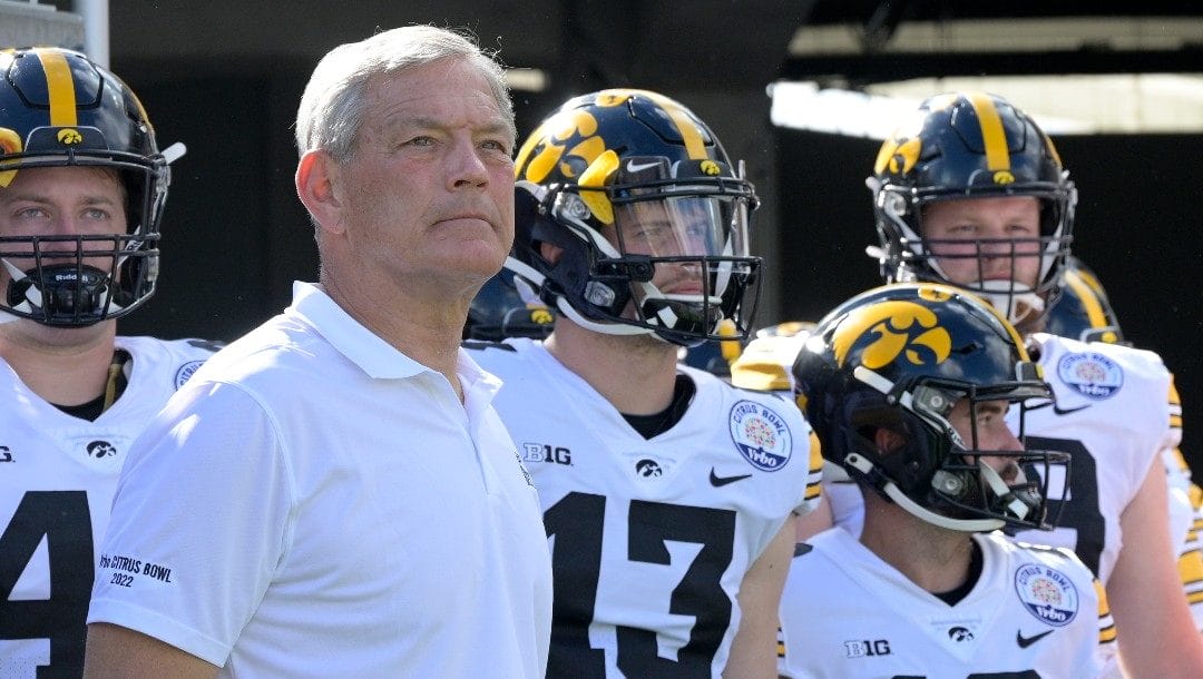 Iowa head coach Kirk Ferentz, front left, waits to take the field with his players before the Citrus Bowl NCAA college football game against Kentucky, Saturday, Jan. 1, 2022, in Orlando, Fla.