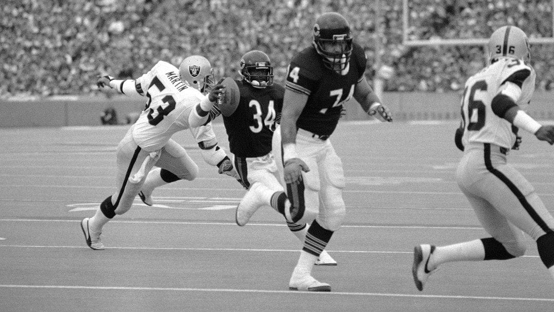 In this Nov. 4, 1984, file photo, Chicago Bears running back Walter Payton, (34), eludes Los Angeles Raiders linebacker Rod Martin (53) as he follows blocking of Bears tackle Jim Covert (74) to score his second touchdown in the first half of an NFL football game at Soldier Field in Chicago.