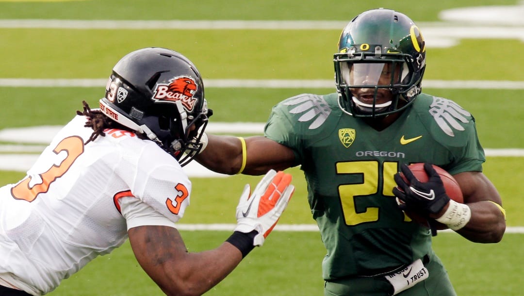 FILE - In this Nov. 26, 2012, file photo, Oregon running back Kenjon Barner, right, holds off Oregon State defender Anthony Watkins during the first half of an NCAA college football game in Eugene, Ore. Barner takes over this season as the top running back for Oregon now that LaMichael James has moved on to the San Francisco 49ers. (AP Photo/Don Ryan, File)