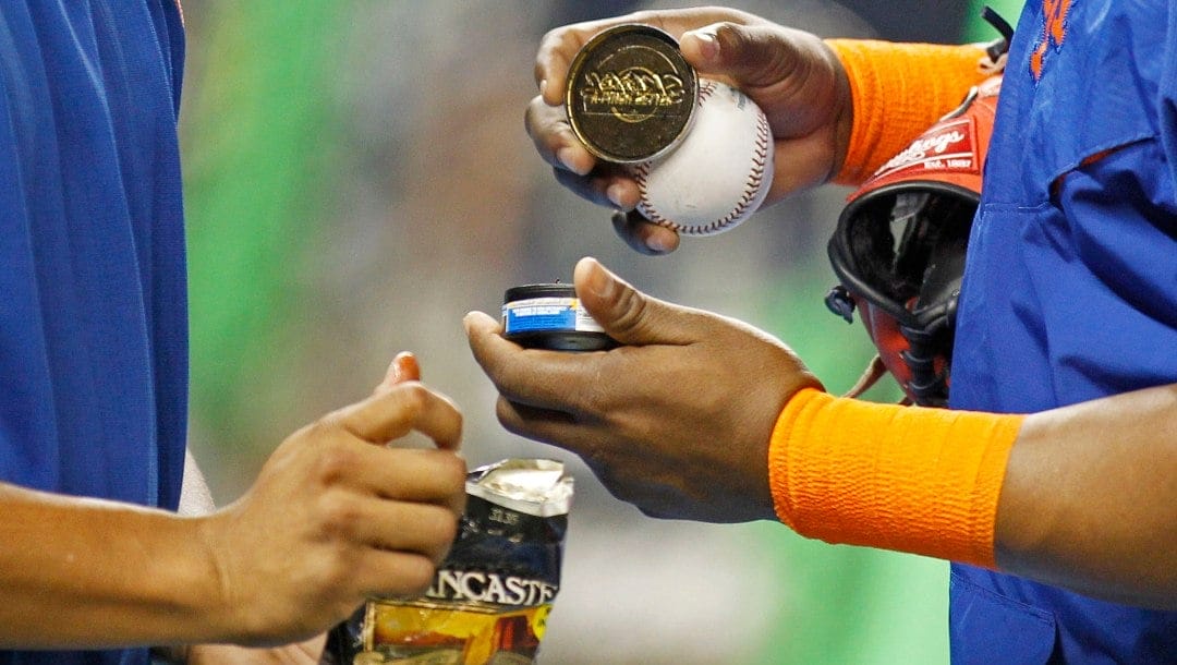 FILE - In this Sept. 5, 2015, file photo, New York Mets players hold tobacco products during batting practice before the team's baseball game against the Miami Marlins in Miami. A person familiar with the negotiations says Major League Baseball and its players' union agreed to ban smokeless tobacco for all new big leaguers. The person spoke on condition of anonymity Wednesday night, Nov. 30, 2016, because the ban is among the details of the sport's new collective bargaining agreement that have not been announced. The ban does not apply to any player who already has at least one day of major league service.