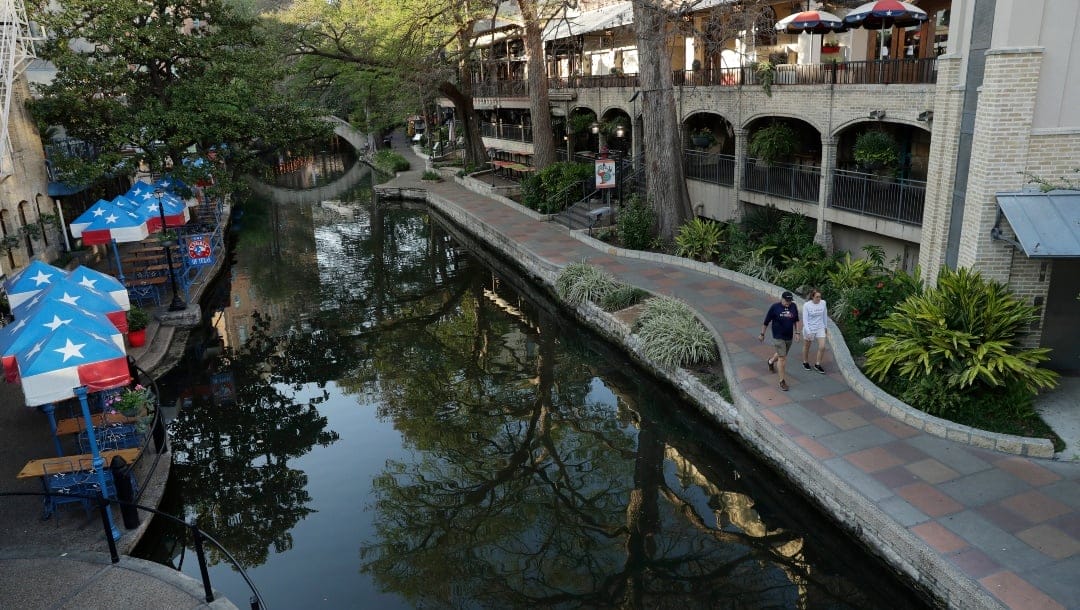 Pedestrians move along a mostly deserted River Walk in San Antonio, Tuesday, March 24, 2020, where most restaurants and business are closed. San Antonio is joining several other major Texas cities and will begin Stay at Home orders at the end of the day Tuesday to help battle the effects of COVID-19. (AP Photo/Eric Gay)