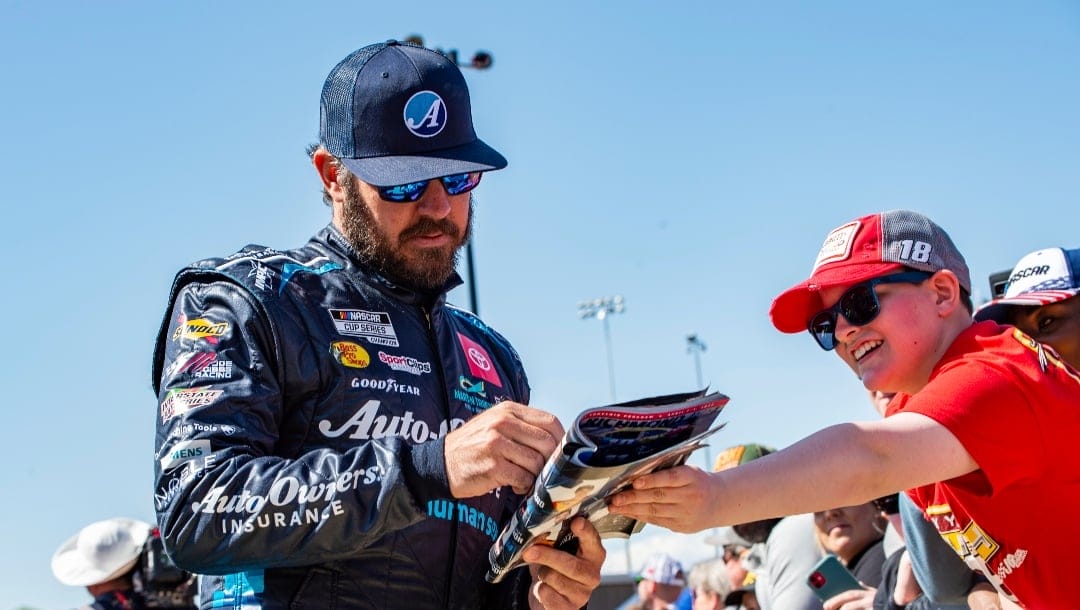 Martin Truex Jr. signs an autograph at a NASCAR Cup Series auto race at Richmond Raceway on Sunday, April 3, 2022, in Richmond, Va. (AP Photo/Mike Caudill)