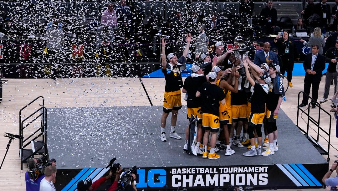 Iowa players celebrate with the trophy after an NCAA college basketball game against Purdue at the Big Ten Conference tournament, Sunday, March 13, 2022, in Indianapolis. Iowa won 75-66. (AP Photo/Michael Conroy)