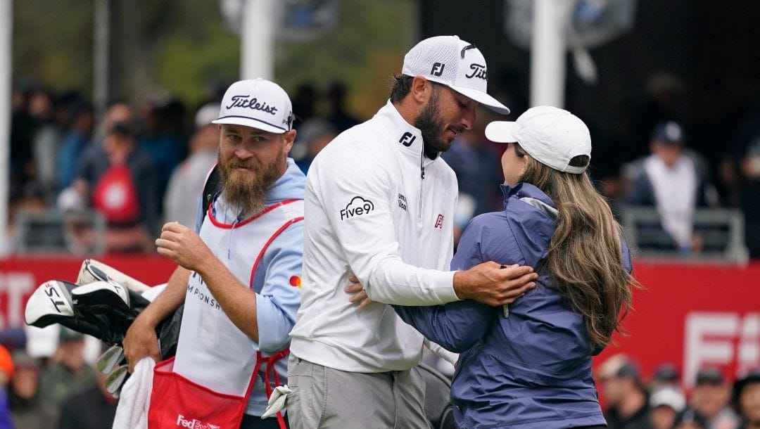 Max Homa, center, is greeted by his wife Lacey, right, on the 18th green of the Silverado Resort North Course after winning the Fortinet Championship PGA golf tournament in Napa, Calif., Sunday, Sept. 18, 2022. Homa's caddie Joe Greiner, left, looks on.