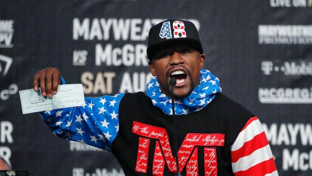 Floyd Mayweather Jr. holds up a check while speaking at a news conference at Staples Center Tuesday, July 11, 2017, in Los Angeles.