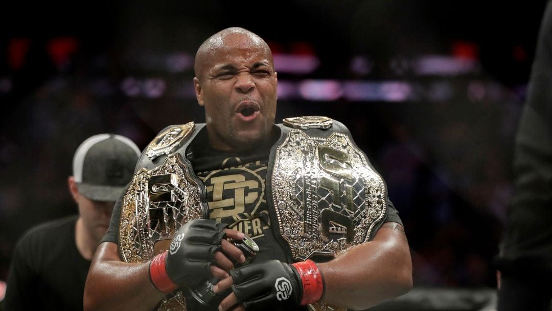 Daniel Cormier holds his belts after defeating Derrick Lewis by submission during the second round of a heavyweight mixed martial arts bout.