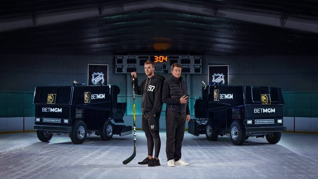 Wayne Gretzky and Connor McDavid in an ice hockey rink, between two BetMGM's branded Zamboni cars.