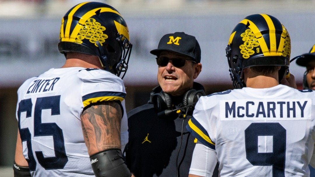 Michigan head coach Jim Harbaugh talks with offensive lineman Zak Zinter (65) and quarterback J.J. McCarthy (9) during an NCAA college football game, Saturday, Oct. 8, 2022, in Bloomington, Ind.