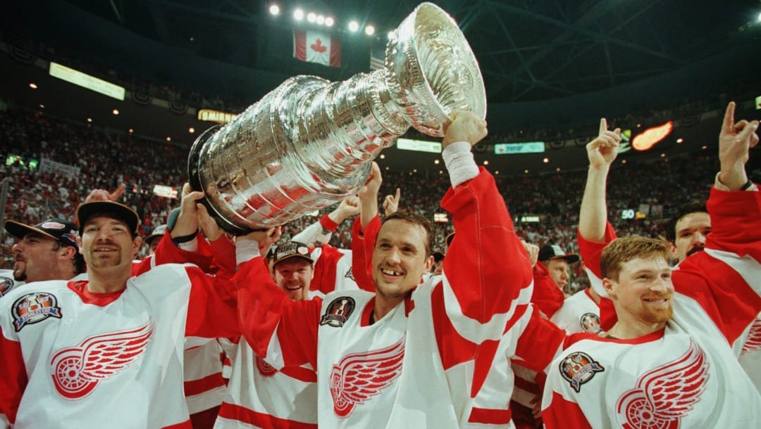FILE - In this June 7, 1997, file photo, Detroit Red Wings' Tim Taylor, from left, Steve Yzerman and Doug Brown celebrate with the Stanley Cup after beating the Philadelphia Flyers 2-1 at Joe Louis Arena in Detroit. Detroit swept the best-of-7 Stanley Cup final series against the Flyers, giving the franchise its first championship since 1955. The arena will be the home of the Red Wings one more time on Sunday, April 9, 2017, when they host the New Jersey Devils. (AP Photo/Tom Pidgeon, File)