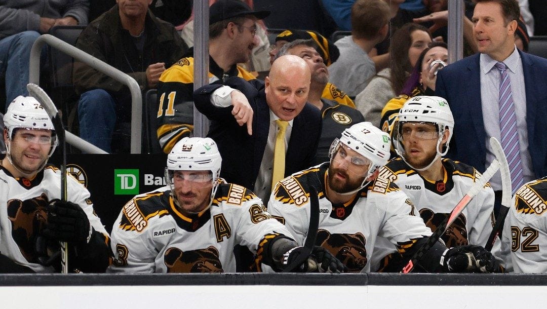 Boston Bruins head coach Jim Montgomery talks with his players on the bench during the second period of an NHL hockey game against the Colorado Avalanche Saturday, Dec. 3, 2022, in Boston.