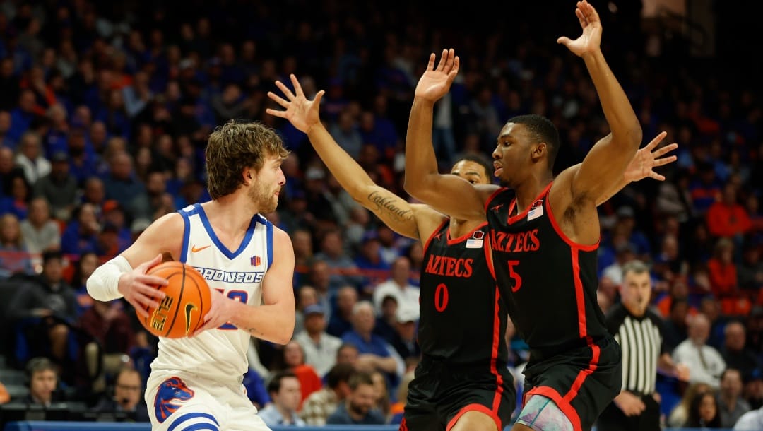 Boise State's Max Rice looks for a pass around San Diego State's Keshad Johnson (0) and Lamont Butler (5) during the first half of an NCAA college basketball game in Boise, Idaho, Tuesday, Feb. 28, 2023. Boise State won 66-60. (AP Photo/Otto Kitsinger)