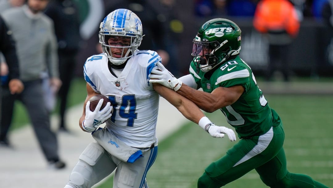 Detroit Lions wide receiver Amon-Ra St. Brown (14) is pushed out of bounds by New York Jets cornerback Michael Carter II (30) during the second quarter of an NFL football game, Sunday, Dec. 18, 2022, in East Rutherford, N.J. (AP Photo/Seth Wenig)