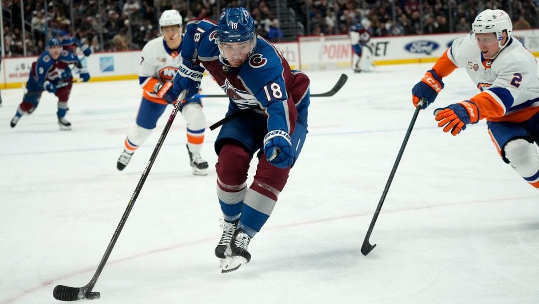 Colorado Avalanche center Alex Newhook, left, drives past New York Islanders defenseman Robin Salo in the third period of an NHL hockey game Monday, Dec. 19, 2022, in Denver.