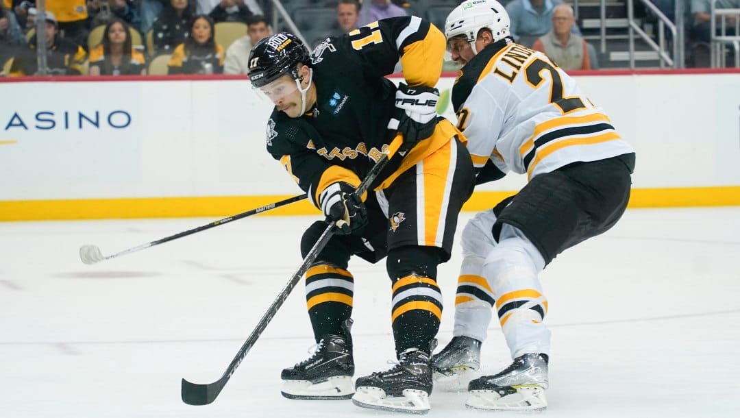 Pittsburgh Penguins' Bryan Rust (17) brings the puck past Boston Bruins' Hampus Lindholm (27) during the second period of an NHL hockey game, Tuesday, Nov. 1, 2022, in Pittsburgh.