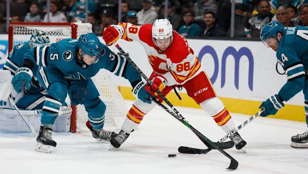 San Jose Sharks defenseman Matt Benning (5) and defenseman Marc-Edouard Vlasic (44) battle for the puck against Calgary Flames left wing Andrew Mangiapane (88) in the second period of an NHL hockey game Sunday, Dec. 18, 2022, in San Jose, Calif.
